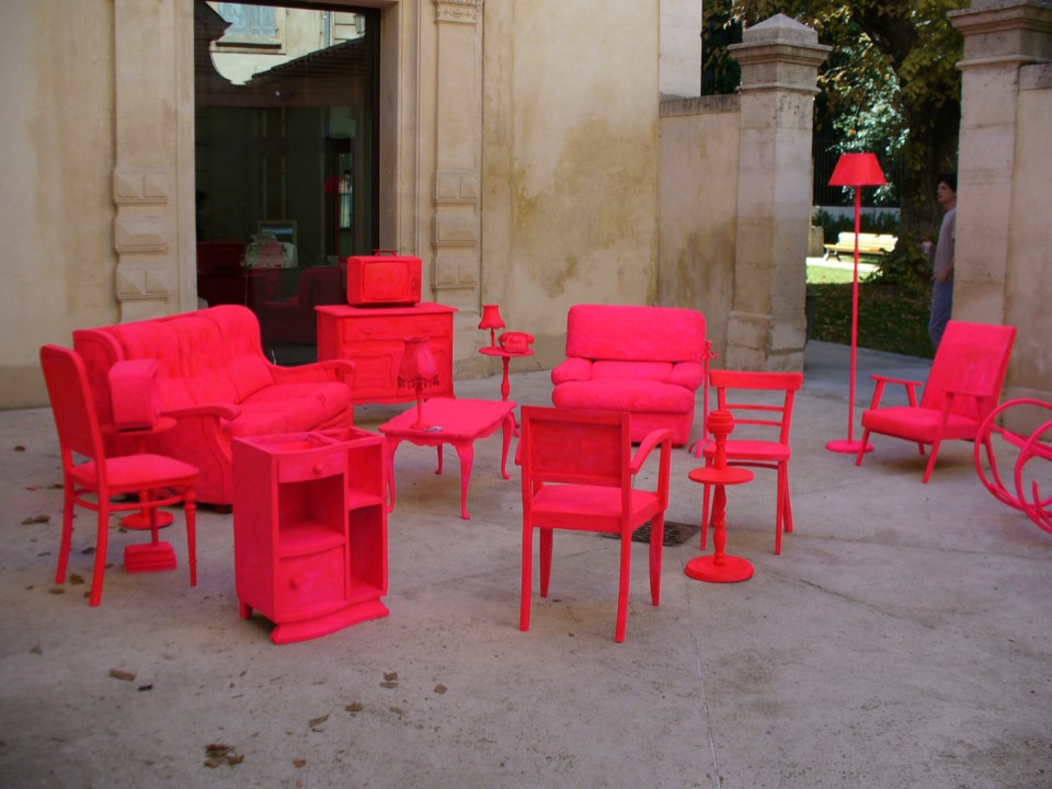 Reclaimed furniture painted bright pink and covered in graffiti assembled in a public courtyard.