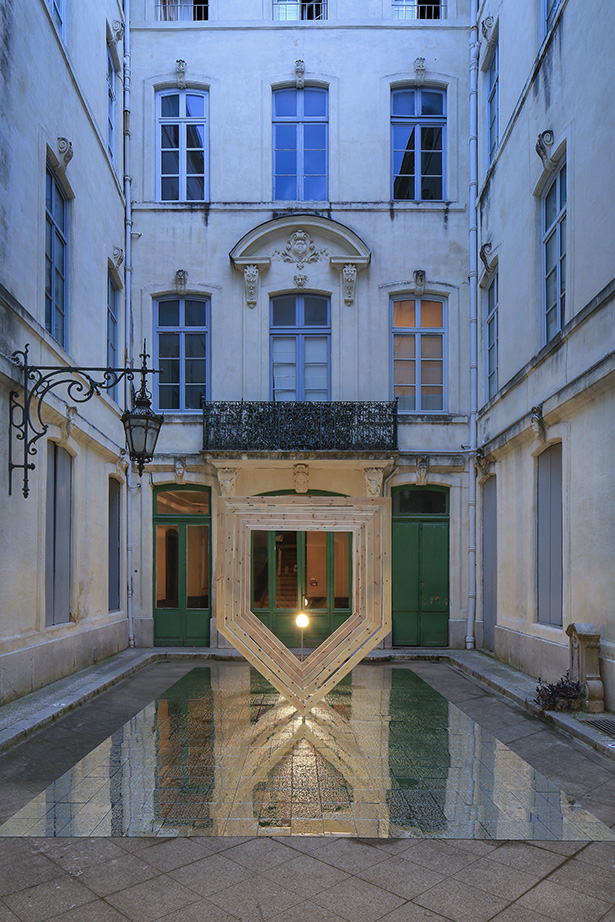 Nested wooden frames hover above a grid of mirrors and a central bulb in a blue-lit courtyard